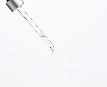 glass pipette with dripping transparent liquid on a white background. Acid, serum