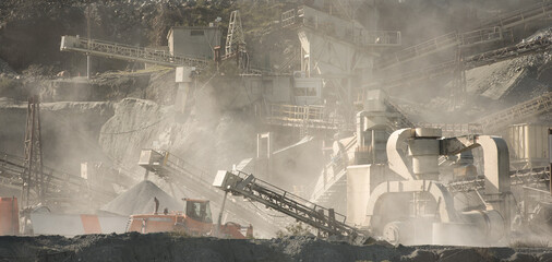 Gravel quarry at work. Stone crushing and screening machinery in clouds of dust