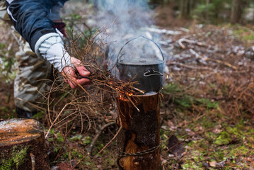 People are going to cook food in a pot on Swedish Fire Log. Burning a Swedish candle, torch in winter evening.