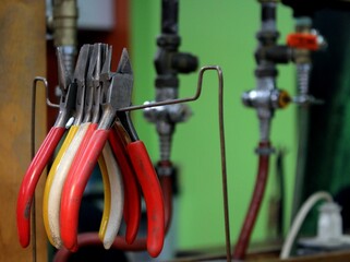 Bright steel metal pliers and snips: metalworking with bright handles and natural gas tubes on the background, installation for a metalwork, craft or jewelry making small business 