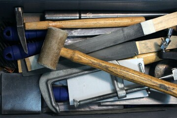 A hammer, sandpaper tools and other jewelry making devices in a toolbox in a jewellery workshop.