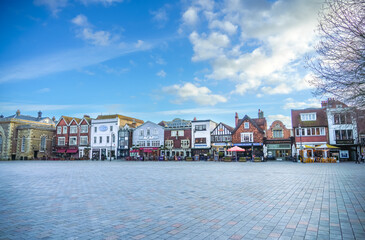 Salisbury England medieval city centre market place square, stone paved with a long row of shops,...