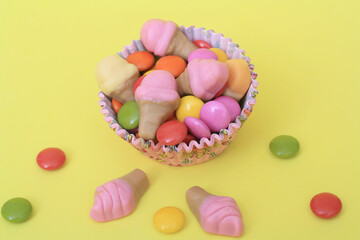 Bright multi colour chocolate gemes on yellow background.