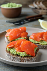 Delicious sandwiches with salmon and avocado on grey plate, closeup