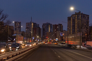 Central street in Kommunarka in winter. A lot of high-rise buildings and a lighted city highway