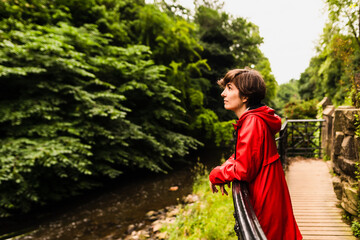 Portrait of a happy young female wearing a red raincoat and witnessing the animals and plants...