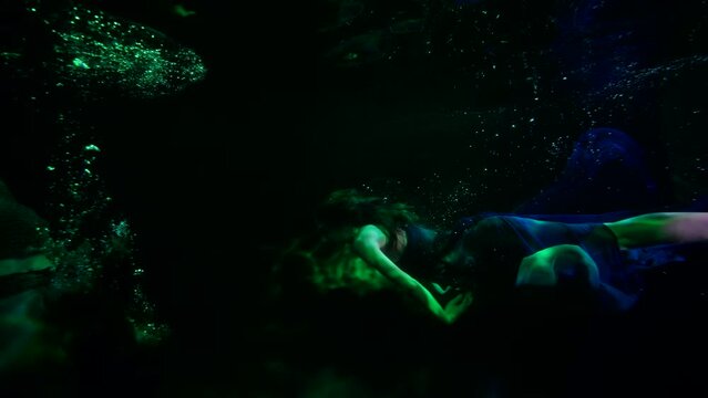two water-nymphs are swimming in dark and mysterious depth of magical sea or river