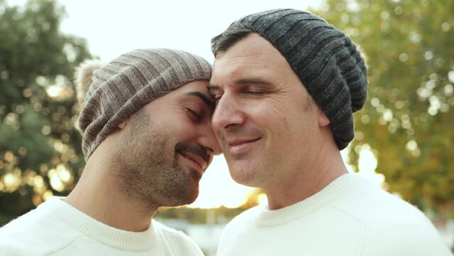 LGBT gay men couple having tender moment outdoor at city park in winter time