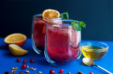 Tea with cranberry, orange, lemon, cinnamon, honey and mint on a blue background. Two glasses with fruit tea and spices