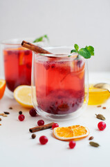 Tea with cranberry, orange, lemon, cinnamon, honey and mint on a white background. Two glasses with fruit tea and spices