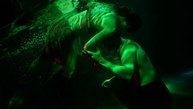 temptress undine is swimming near sinking sailor and alluring him, underwater shot