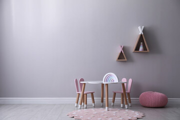 Cute child room interior with furniture, toys and wigwam shaped shelves on grey wall. Space for text © New Africa