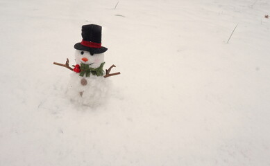 White Snowman with Twig Arms and Black Hat with Scarf on Snow
