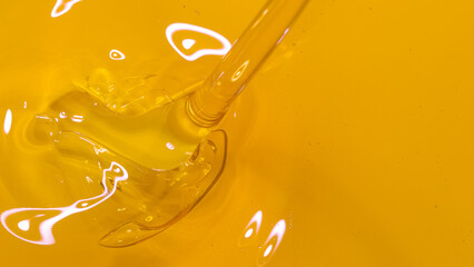 TOP DOWN, DOF: Shiny unrefined organic flaxseed oil flows into a golden barrel.