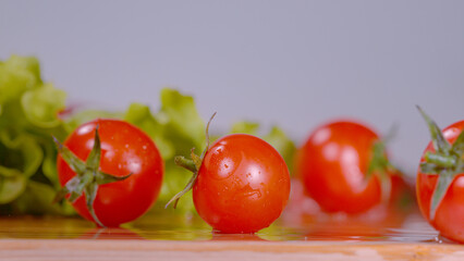 MACRO: Washed salad ingredients are rolling around the wooden kitchen countertop