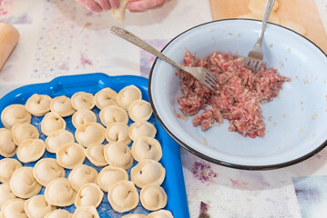 Sculpt dumplings with your hands. The woman is preparing food. Traditional Russian cuisine. Raw dumplings. Delicious homemade food.