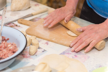 Roll out the dough. A woman rolls the dough with a rolling pin. Cooking food. Traditional dishes.