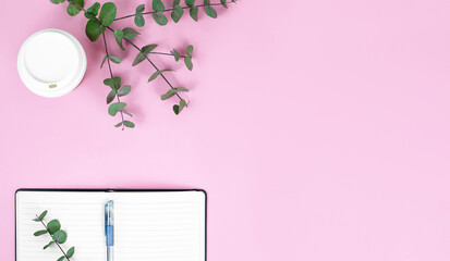 flat lay banner of notebook, take away cup, pen and green leaves on blue background with copy space. education concept