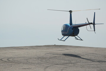 Blue helicopter flying in grey cloudy skies. High quality photo