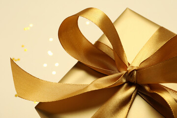 Beautiful golden gift box on beige background, closeup
