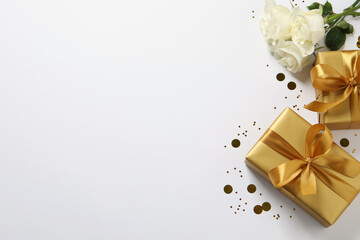 Beautiful golden gift boxes, flower and confetti on white background, flat lay. Space for text