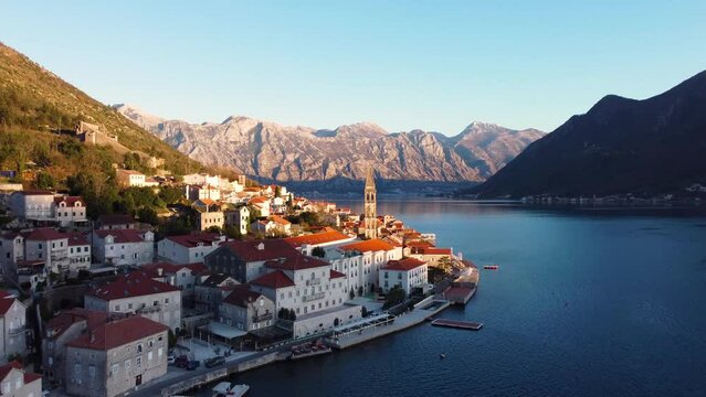 Panoramic sunset aerial drone view of the ancient city of Perast, Montenegro.Old medieval town with red roofs and with majestic mountains on background.Picturesque Kotor bay, coast of Adriatic sea.