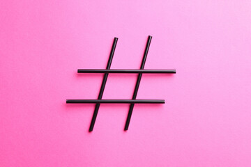 Hashtag symbol made of drinking straws on pink background, top view