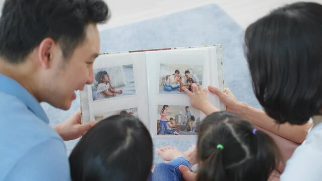 Asian family look at photographs on old picture album recalls the past. 