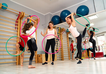 Female dance teachers showing a boy and a girl how to play with hula hoop in the gym, choreography learning, dancing and having fun  © phoenix021