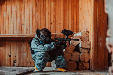 Photo of paintball player in goggle mask and camouflage aiming by paintball gun. Selective focus © Minet