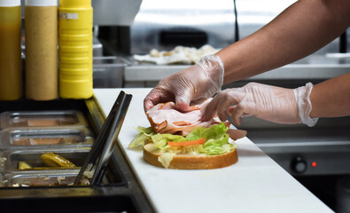 Kitchen employee preparing sandwich for customer food order