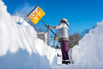 Woman shoveling snow out of driveway with movement and action.