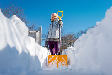 Portrait of woman with snow shovel. Woman shoveling snow out of driveway. 