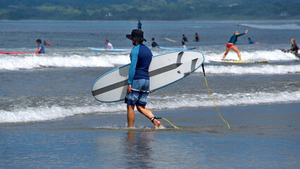 Man carrying a surf board in Tamarindo, Costa Rica