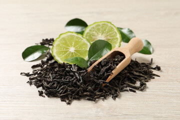 Pile of dry bergamot tea leaves and fresh fruit on light wooden table