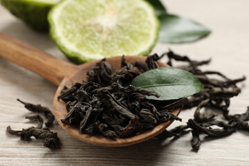 Dry bergamot tea leaves and fresh fruit on light wooden table, closeup