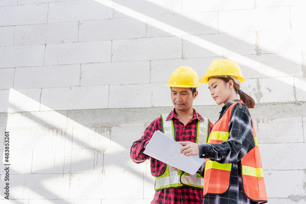 Poster architect and client discussing the plan with blueprint of the building at construction site. asian 