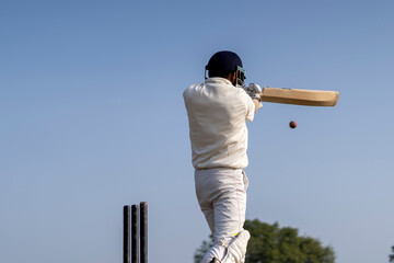 A cricketer playing cricket on the pitch in white dress for test matches. Sportsperson hitting a shot on the cricket ball. - Powered by Adobe