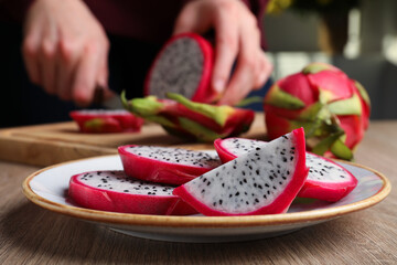 Plate with delicious cut white pitahaya fruit on wooden table indoors, closeup