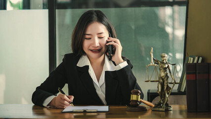 Young Asian lawyer calls her clients about legal contract documents.