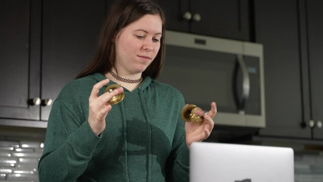 Smiling woman takes remote lesson to learn finger cymbals online on a laptop. Remote learning concept.