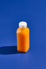Orange juice bottle on blue background. Drink in plastic bottle. Delivery drink. Trendy mock up...