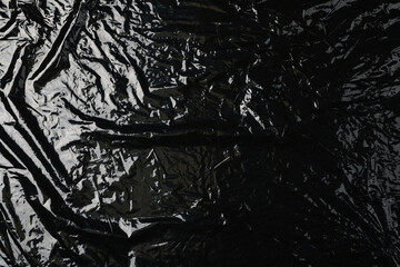 Black plastic stretch wrap film as background, top view