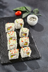 Fresh maki sushi on dark stone table. Colorful roll with vegetables. Sushi roll with salmon,...