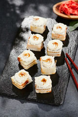 Maki sushi on dark slate. Unagi maki with eel. Sushi roll with eel fish, cream cheese and unagi sauce. Style concept japanese menu with black background, leaves and hard shadow.