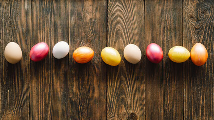 Obraz premium Multicolored Easter eggs on a wooden background. Easter background. Copy space. Easter eggs flat lay on rustic table. Easter concepts