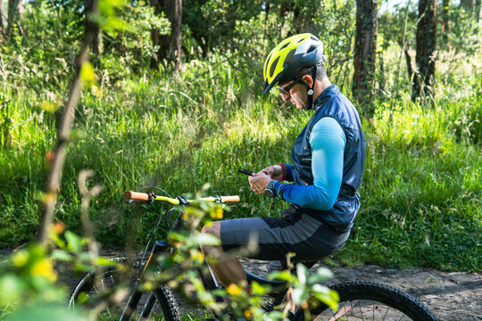 Male mountain biker in his 30s and 40s checking an app on his smartphone in the middle of the forest