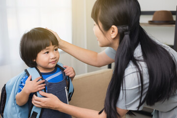 Happy mother conversation and saying goodbye to little boy with school bag at home. First day at school. Back up to school concept.