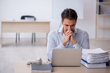 Naklejka premium Young male employee and too much work in the office