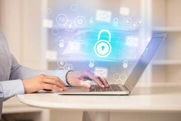 Hands working on laptop with digital icons